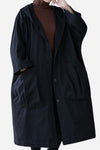 A person dressed in a Black One Size Fits All Oversized Water Resistant Windbreaker Jacket by looselyboho, featuring large front pockets and visible buttons, is wearing it over a brown turtleneck sweater. The stylish jacket is paired with black pants against a solid light background.