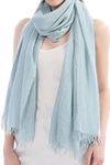 A person wearing a Color-POP Scarf by looselyboho draped around their neck, the soft texture and subtle fringes adding a touch of elegance. Paired with a sleeveless white top, this look is perfect for all-weather versatility, though it's clear no jackets are needed for this stylish ensemble.