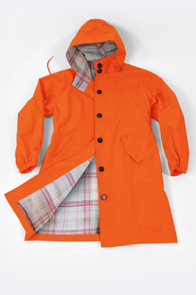 The PUMPKIN ORANGE WINDBREAKER from looselyboho is a stylish raincoat with a hood, complete with a button-up front and two spacious pockets. This lightweight jacket showcases an interior lined with a red and gray plaid pattern, making it ideal for breezy days. Laid flat against a neutral background, it combines vibrant color with functional style.