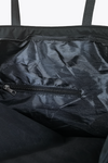 An image showcasing the interior of "The One" Urban Slate Waterproof Travel Bag by looselyboho features a black, lightweight waterproof bag with a visible zipper pocket. The interior fabric has a slightly wrinkled appearance, and the closed zipper is clearly shown. The reinforced handles and straps are partially visible at the top of the image.