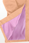 A close-up of a beige stylish **looselyboho PEACH FUZZ WINDBREAKER** with a partial view of its inner lining, which is purple. The lightweight water-resistant material is folded open at the seam, showcasing the contrast between the beige exterior and the purple interior. The background is plain white.